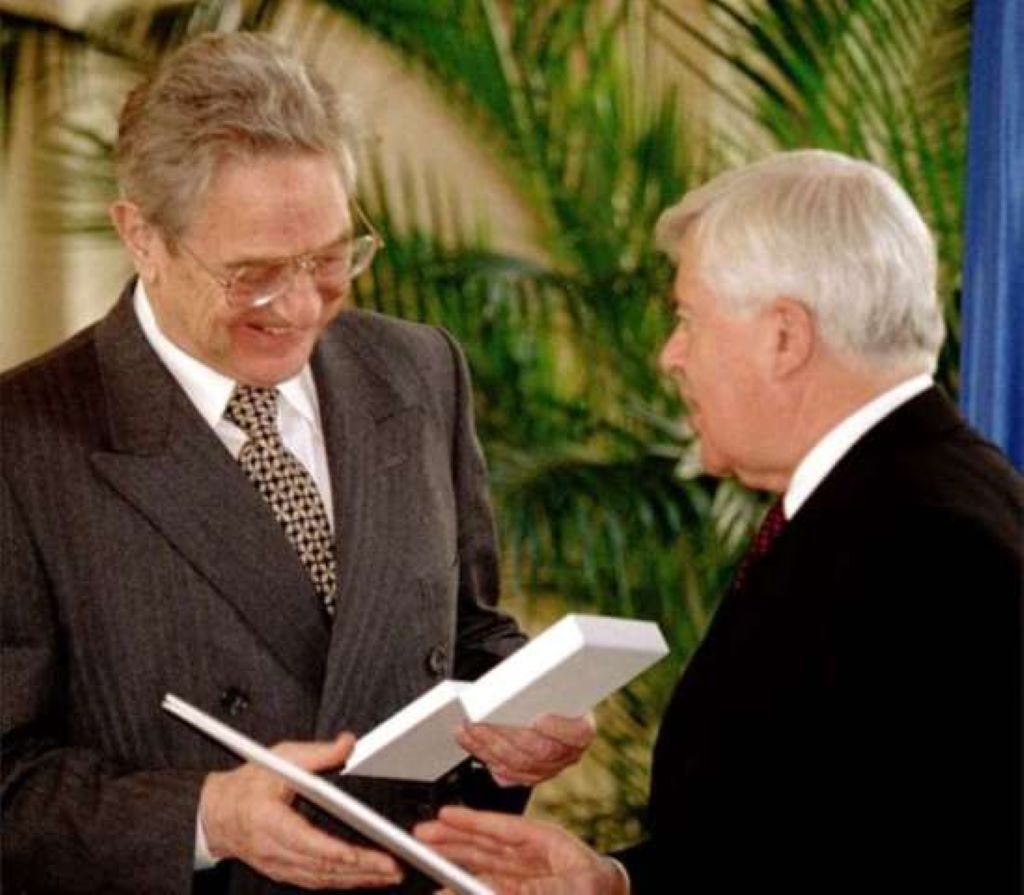 
				George Soros ob prejetju državnega odlikovanja s strani prvega predsednika samostojne Slovenije Milana Kučana. (Foto: Posnetek zaslona- Časnik, STA)			